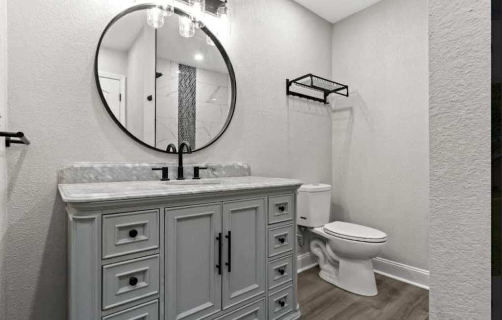 A bathroom with a sink , toilet and mirror.