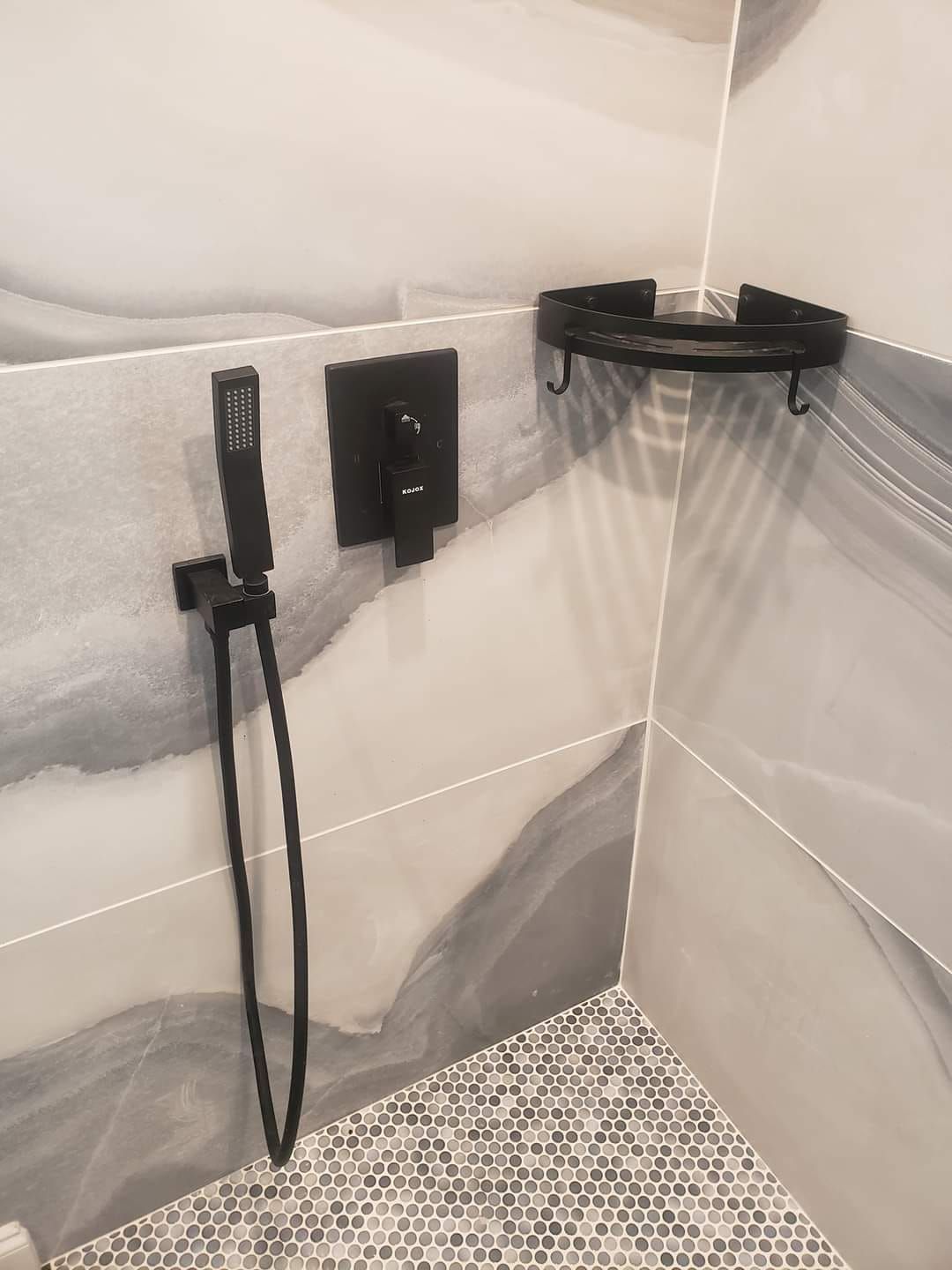 A bathroom with a shower head and a shelf on the wall.