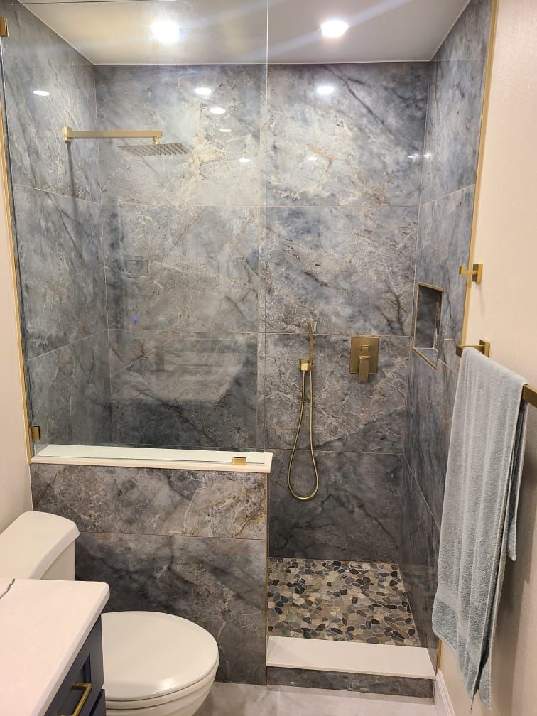 A bathroom with a walk in shower , toilet , sink and mirror.