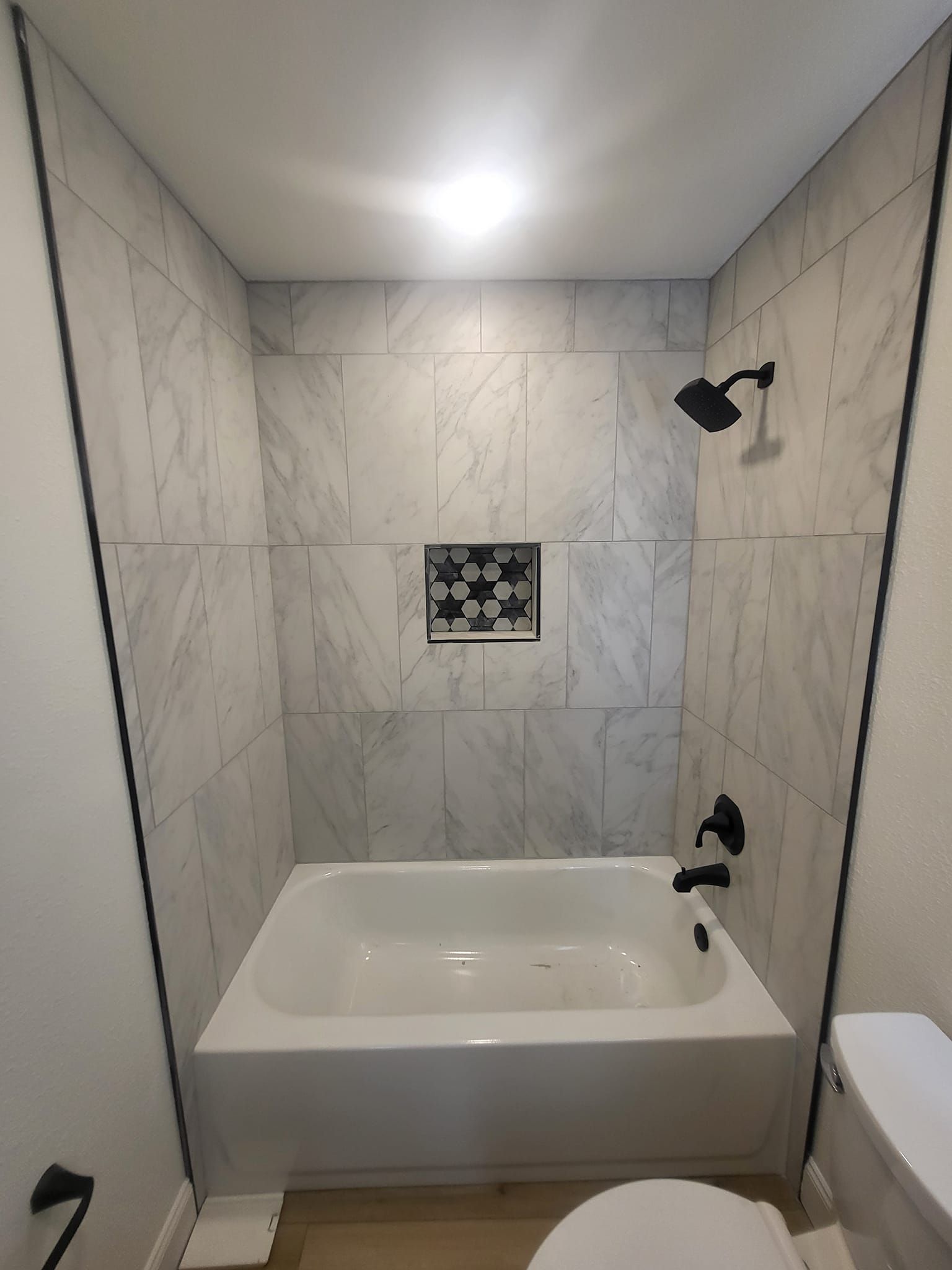 A bathroom with a bathtub , toilet and shower.