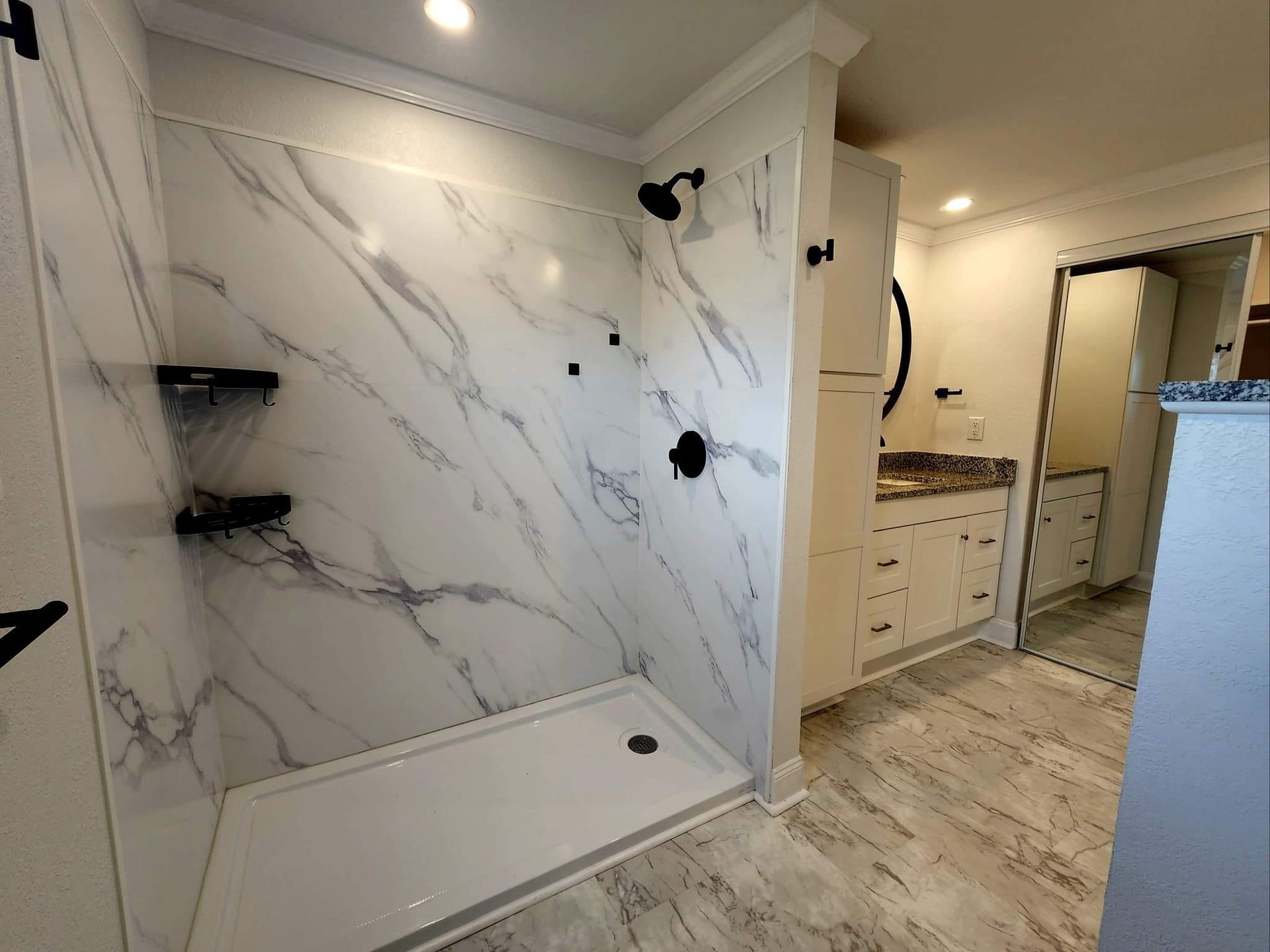 A bathroom with a walk in shower and marble walls.