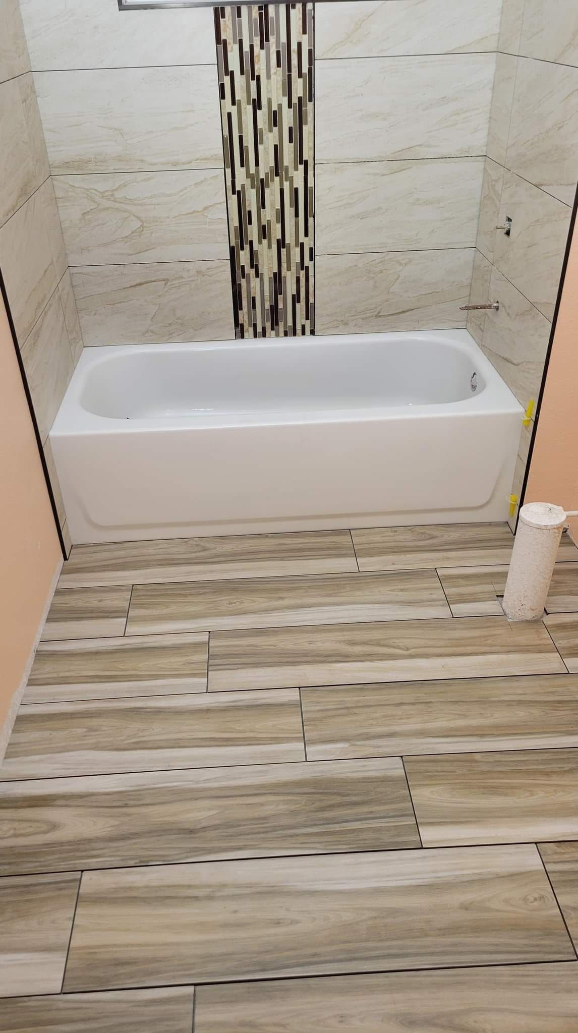 A bathroom with a bathtub and a wooden floor.