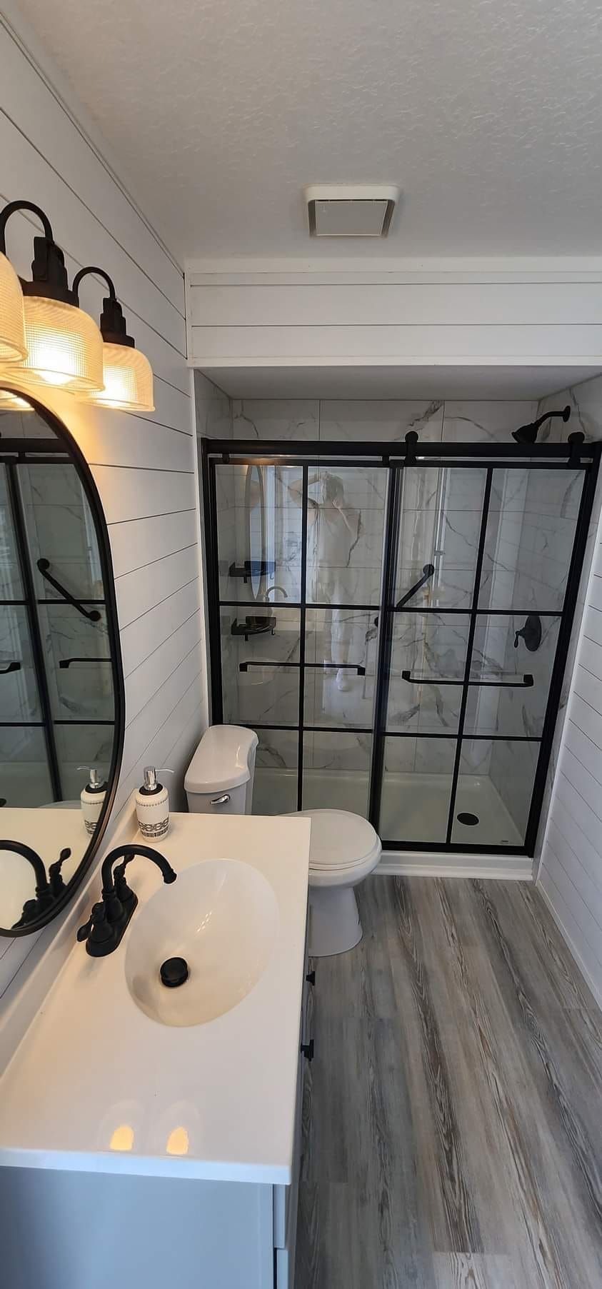 A bathroom with a sink , toilet , shower and mirror.