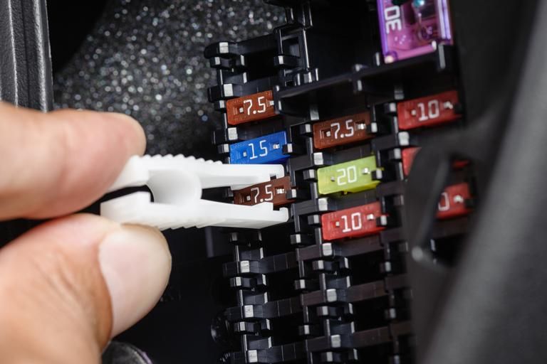 A Close Up of a Person Holding a Fuse in a Fuse Box — Regional Auto Electrics In Fairy Meadow, NSW
