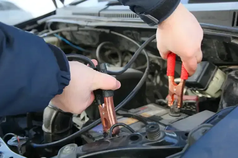A Man is Working on a Car Battery With the Hood Open — Regional Auto Electrics In Fairy Meadow, NSW