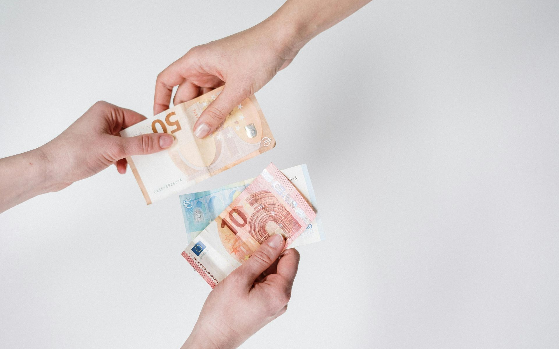 Hands exchanging Euro banknotes on a white background.