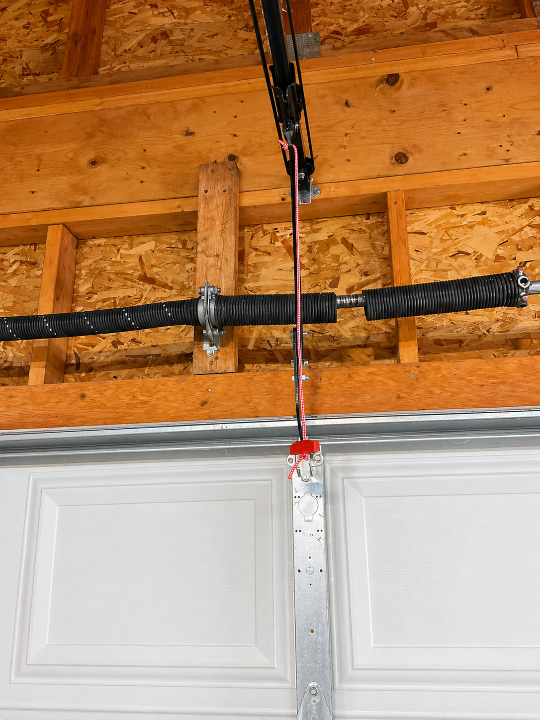 Garage wall with mounted garage door opener hardware, tracks, and a car roof in the foreground