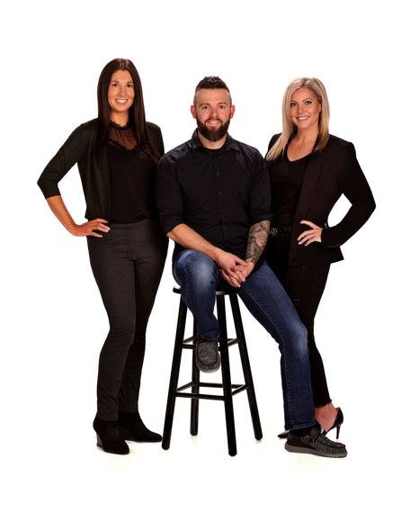 A man is sitting on a stool next to two women