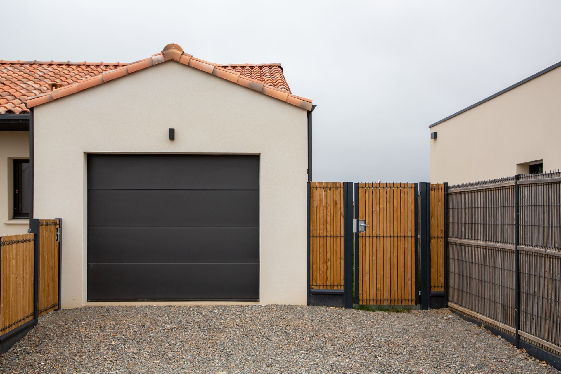 There is a garage with a black door and a wooden gate.