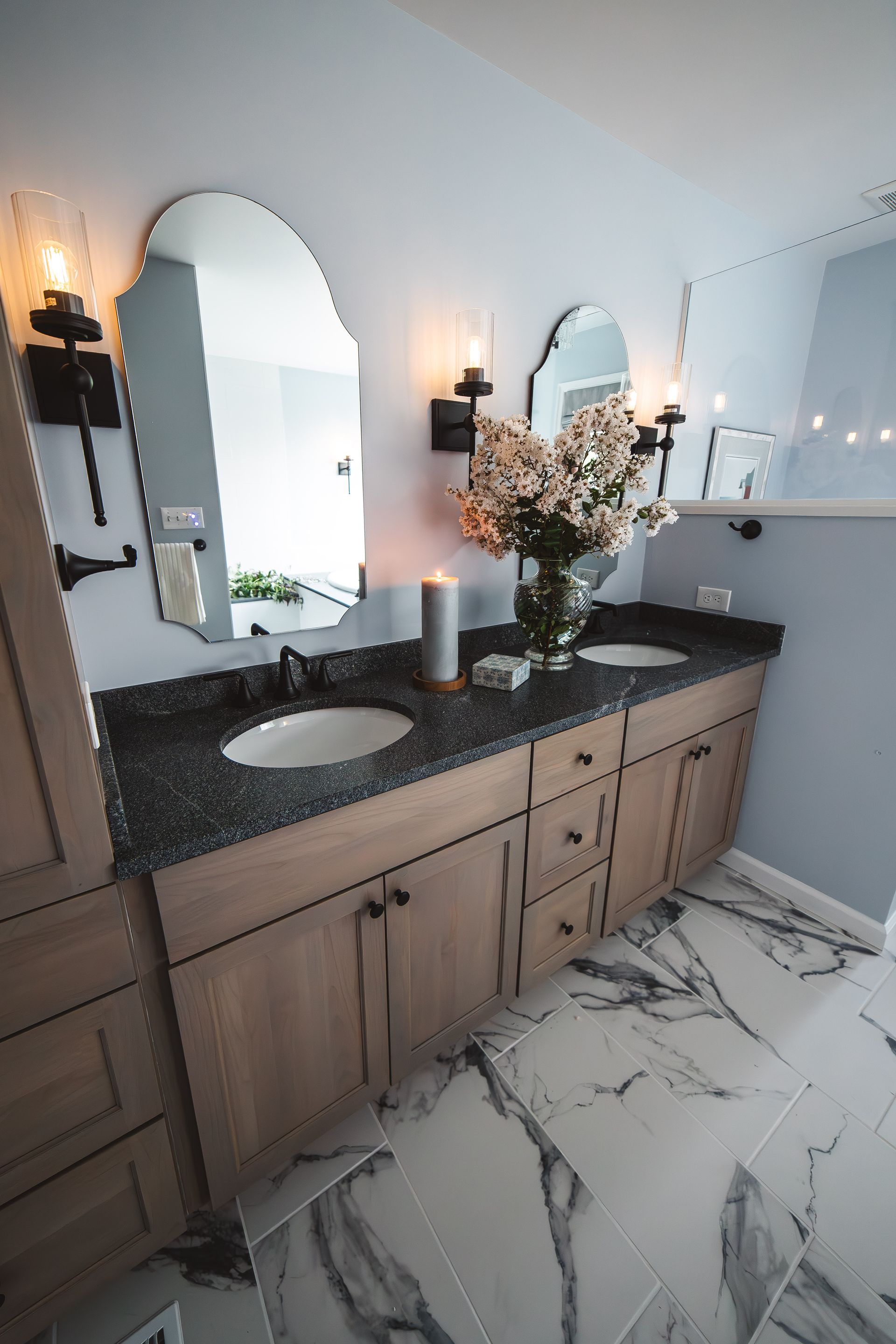 Delray Project - bathroom with two sinks , two mirrors , a vase of flowers and a candle.
