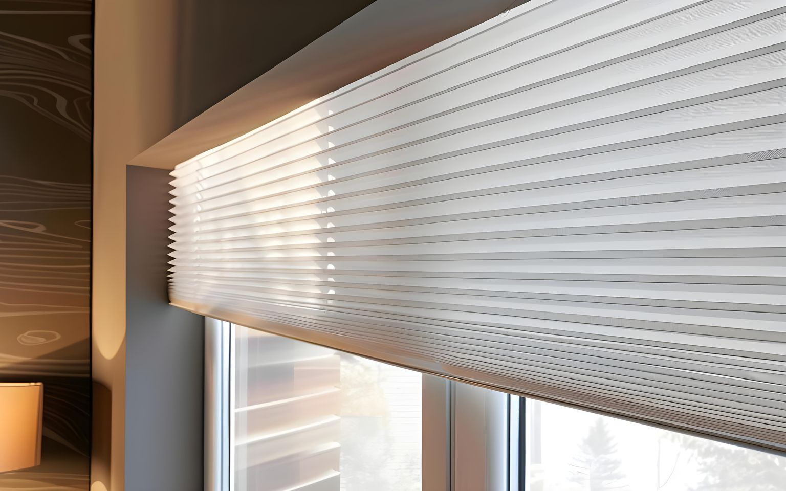 White, horizontal honeycomb pleated blinds partially covering a window in a contemporary room.