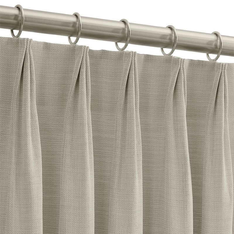 Close-up of light gray pleated curtains on a metal rod with silver rings