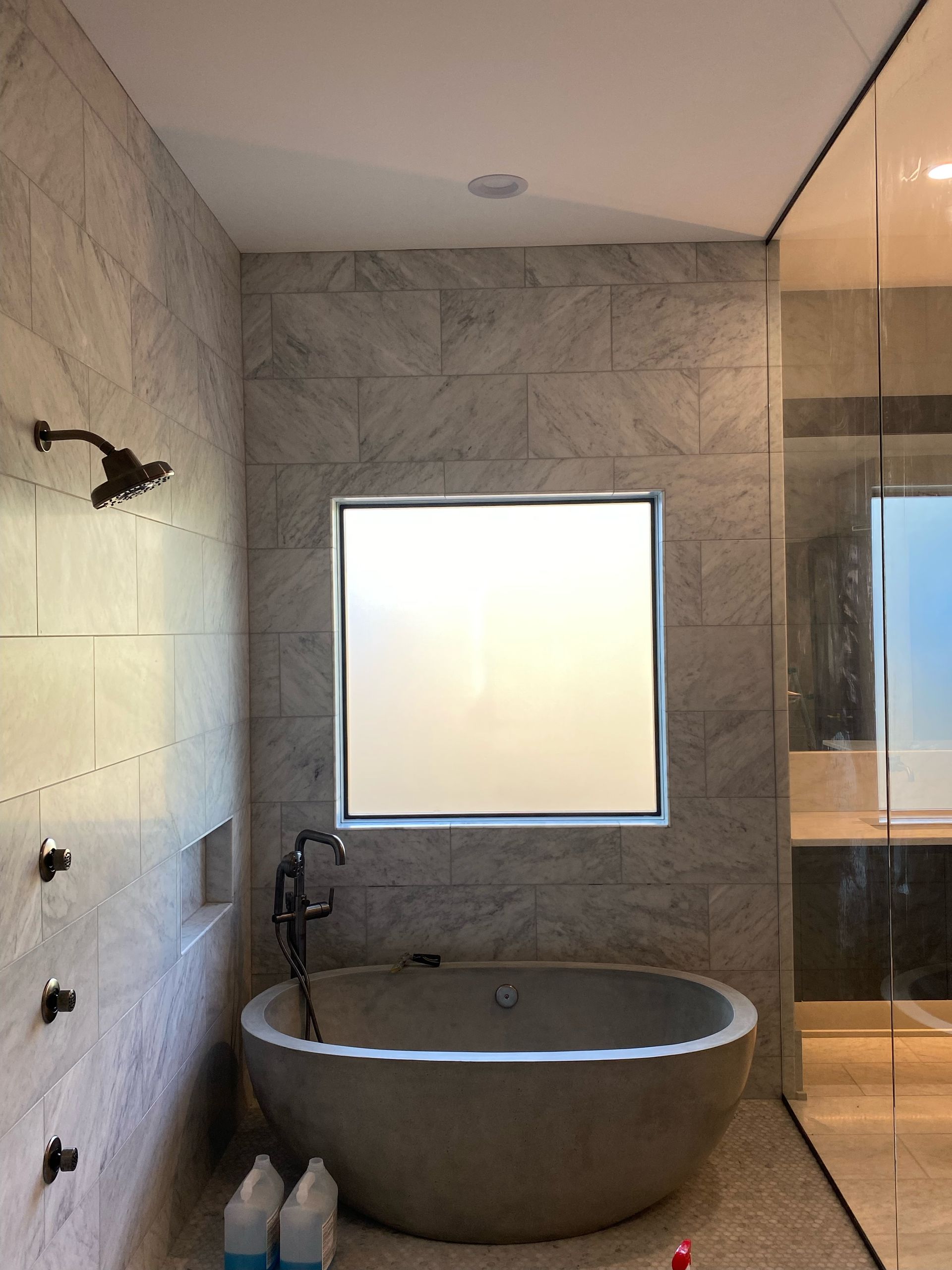 Modern bathroom with a freestanding tub, shower, and frosted window.