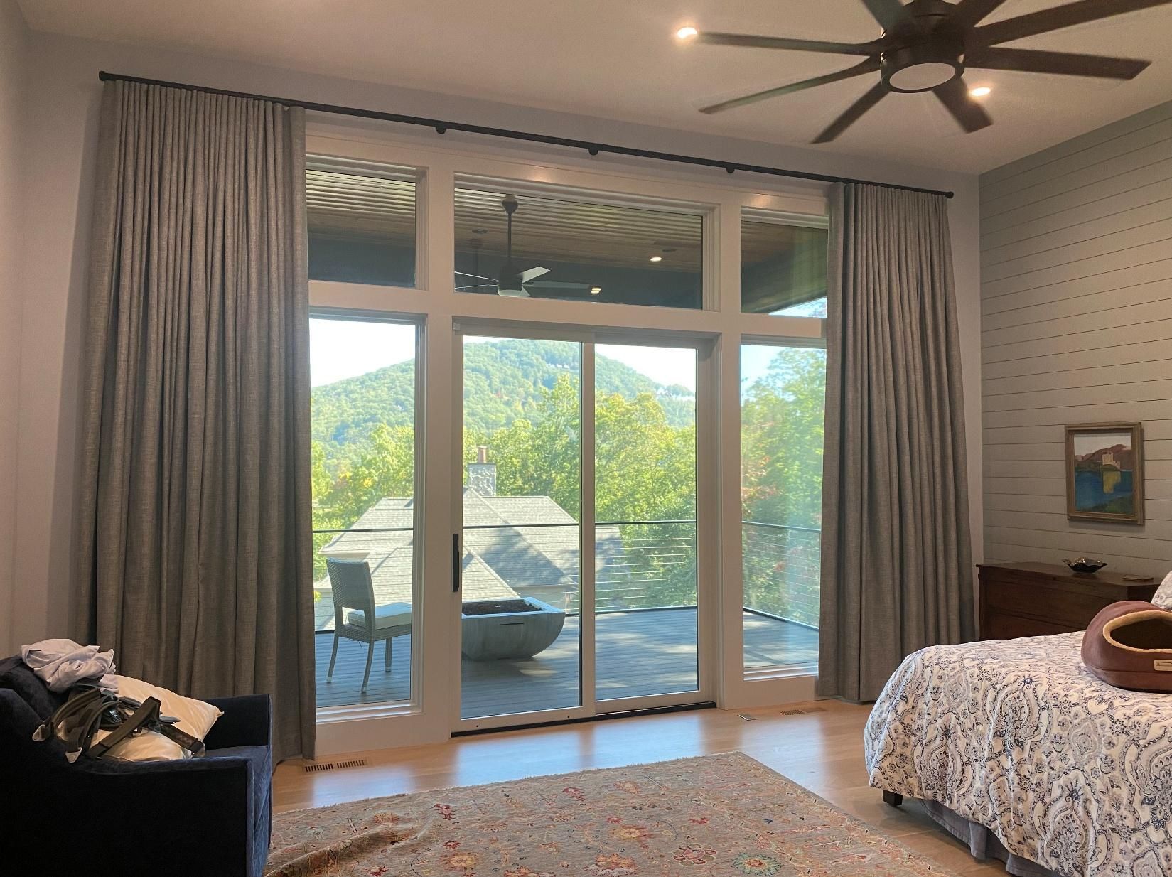 Bright bedroom with sliding glass doors opening to a sunlit patio and trees outside.