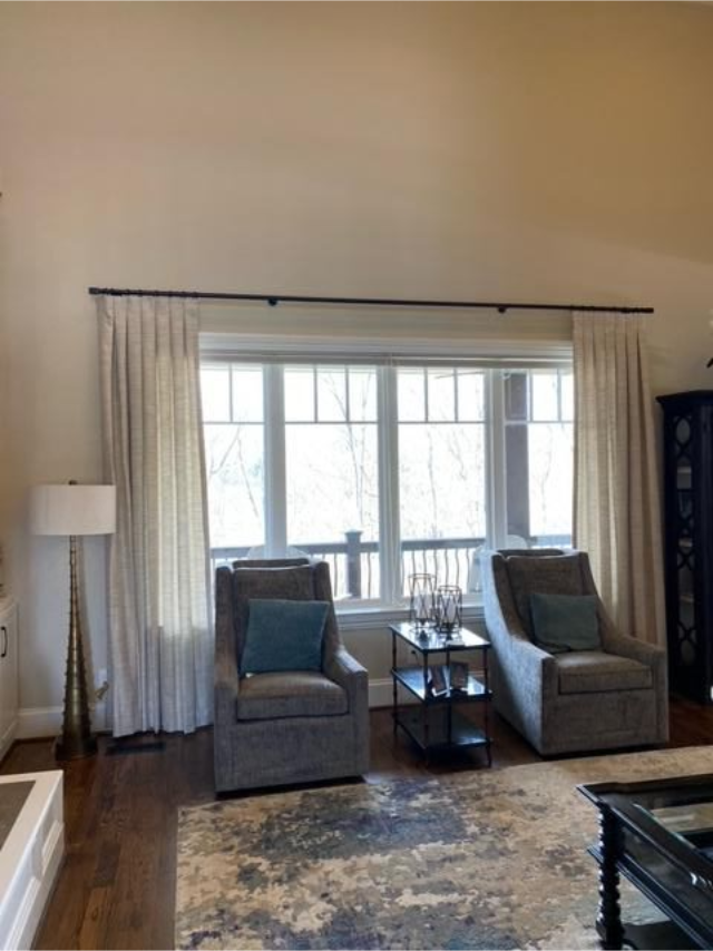 Bright living room with two gray chairs, a large window, floor lamp, rug, and glass coffee table