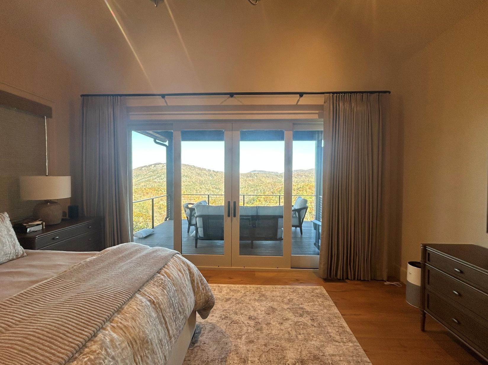Bedroom with a bed, rug, dresser, and sliding glass doors opening to a patio and hillside view