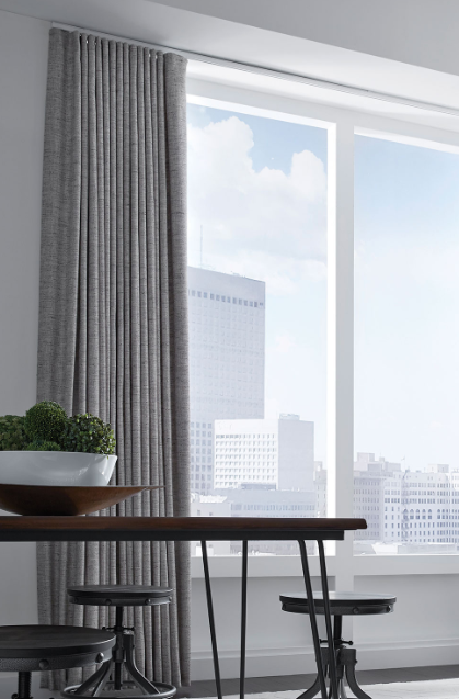 Bright dining area with a table, chairs, potted plant, and large window overlooking city buildings