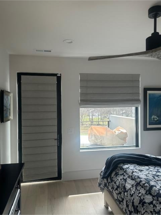 Minimal bedroom with a bed, window, and closed door, in gray and black tones.