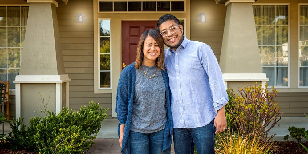 Couple smiling in front of house | GO Property Management