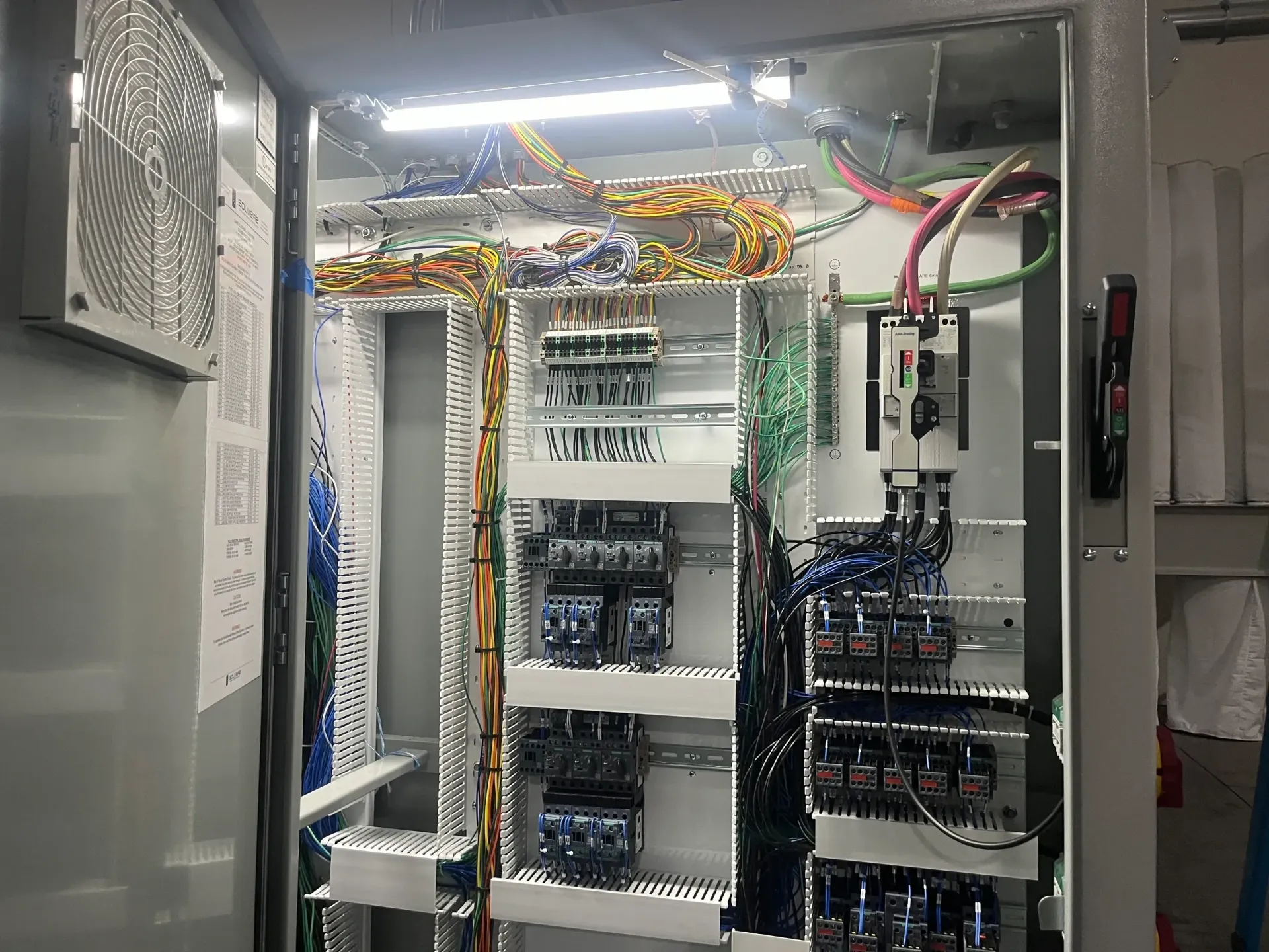 Inside an electrical control panel with various colored wires, and components.