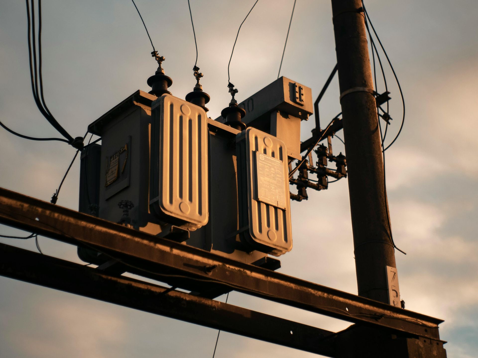Power transformer atop a utility pole against a dusky sky.