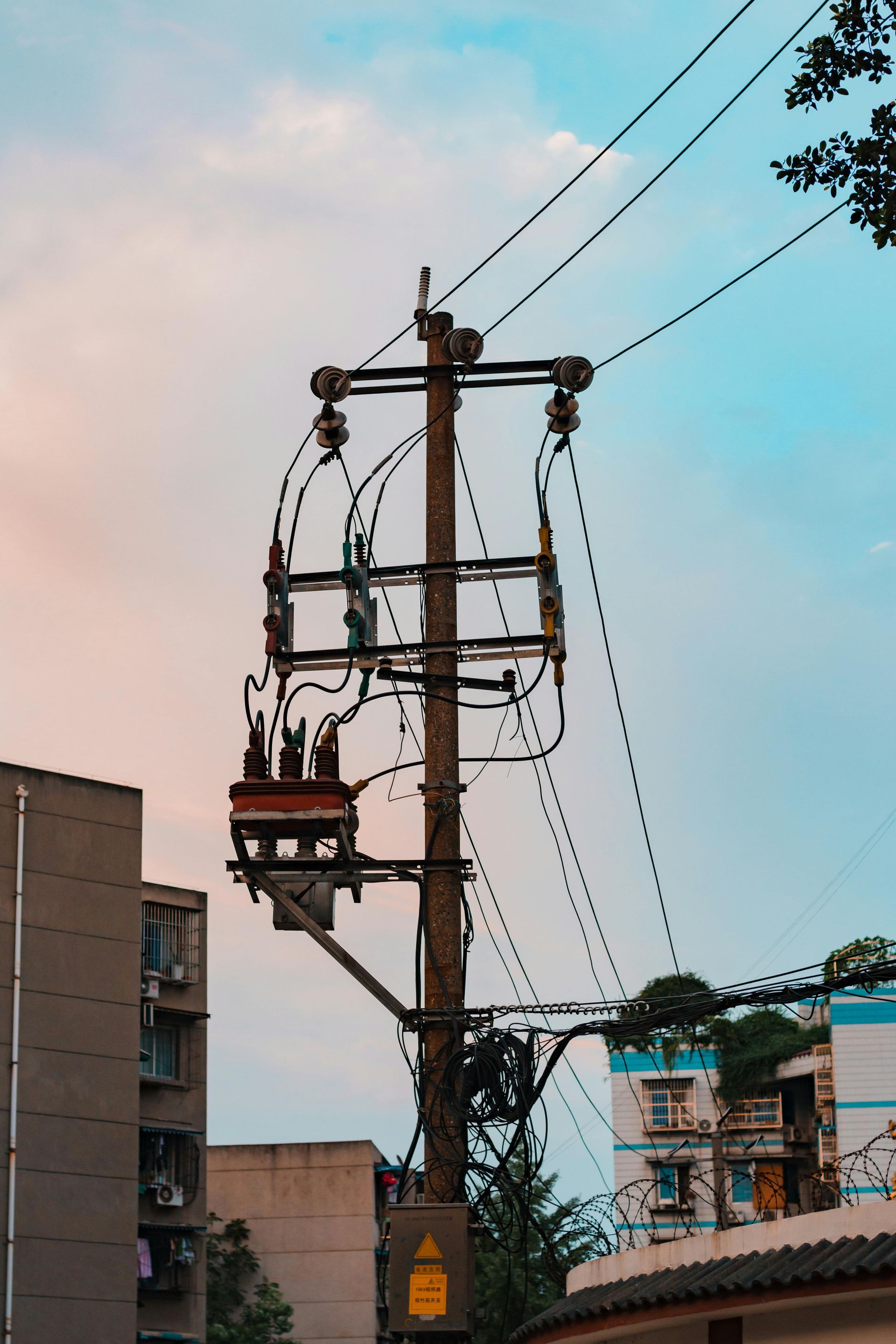 Utility pole with wires against a colorful sky. Buildings in the background.