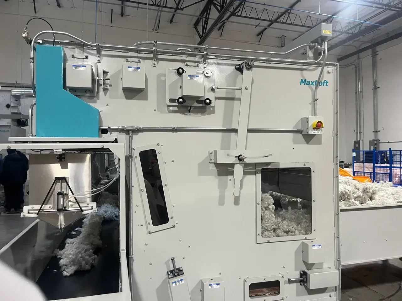 Large industrial machine processing cotton in a factory setting, with blue and white components.