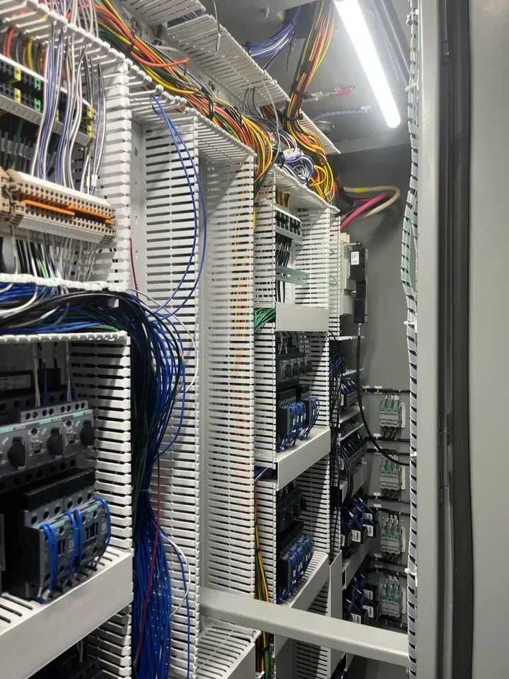 Inside of electrical control panel with organized wiring and components.