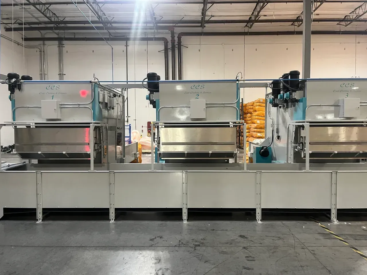 Industrial machinery in a factory setting, with multiple stainless steel vats and mechanical components.