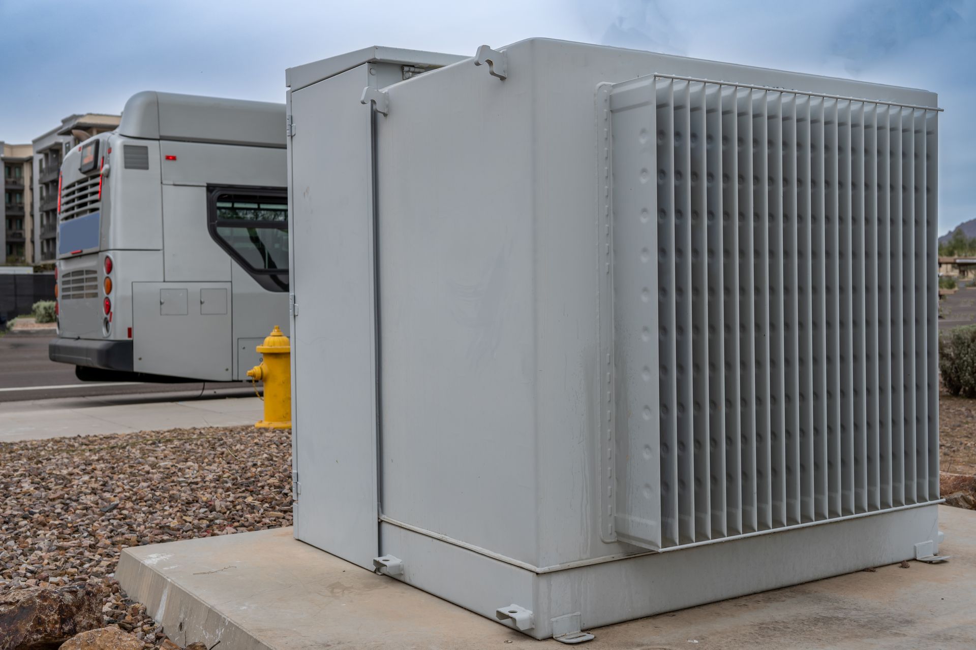 Power transformer mounted on a utility pole against a cloudy sky.