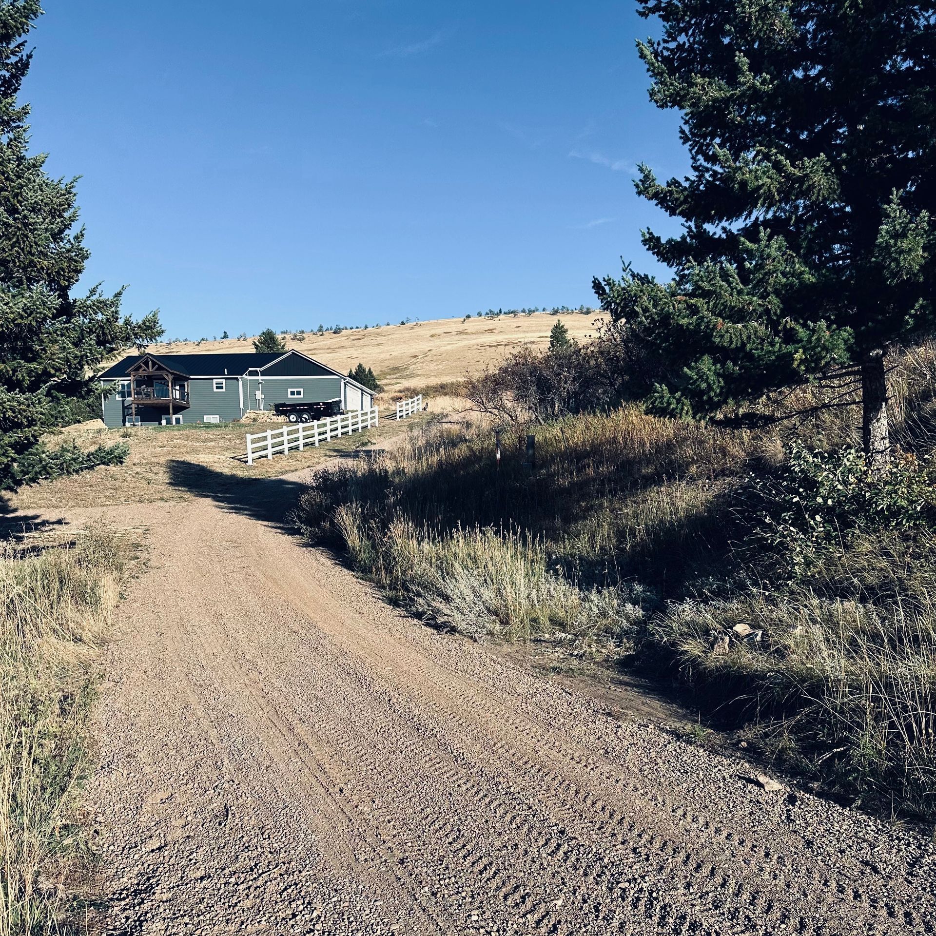 A dirt road leads to a house on top of a hill