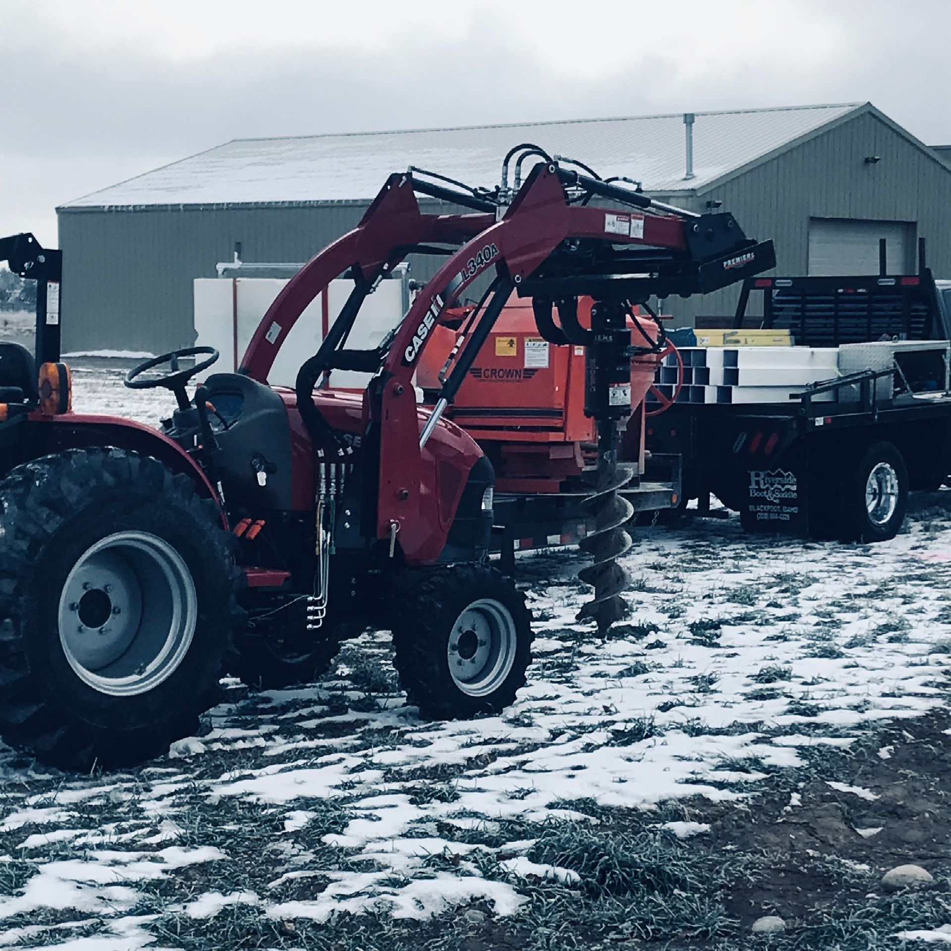A tractor with a crane attached to it is parked in the snow