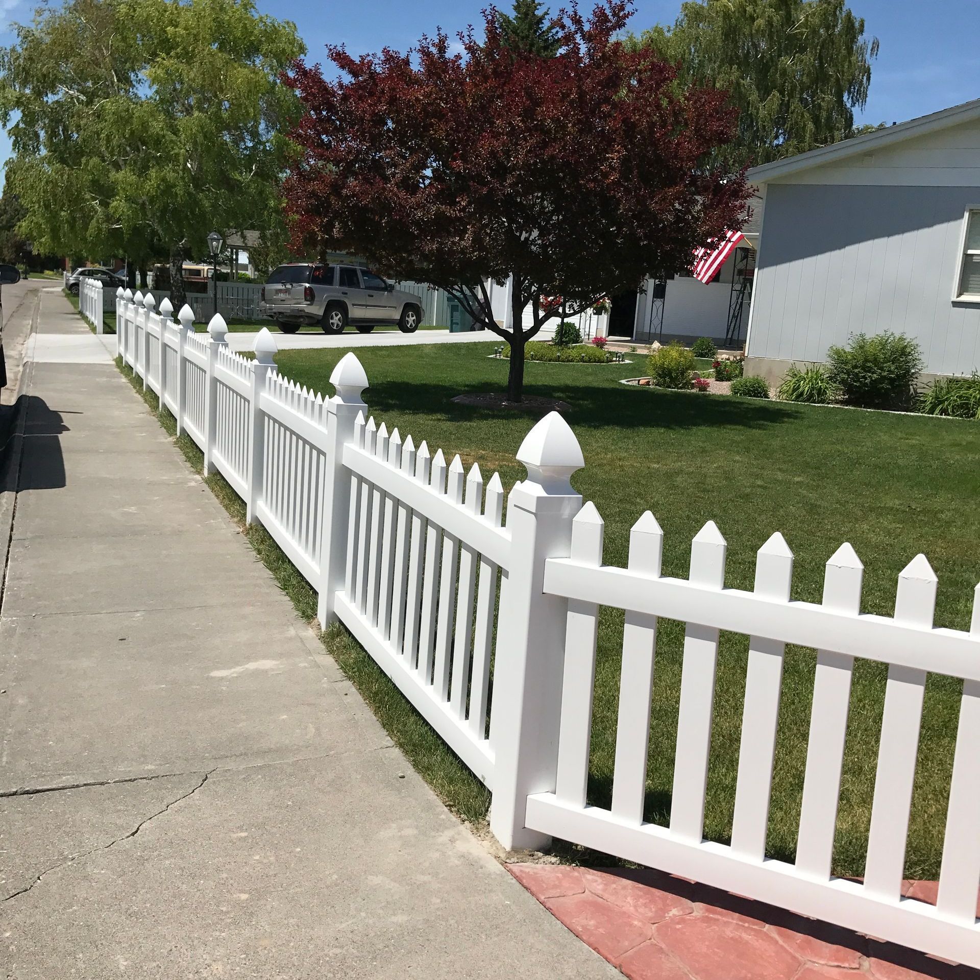 A white picket fence along a sidewalk in front of a house