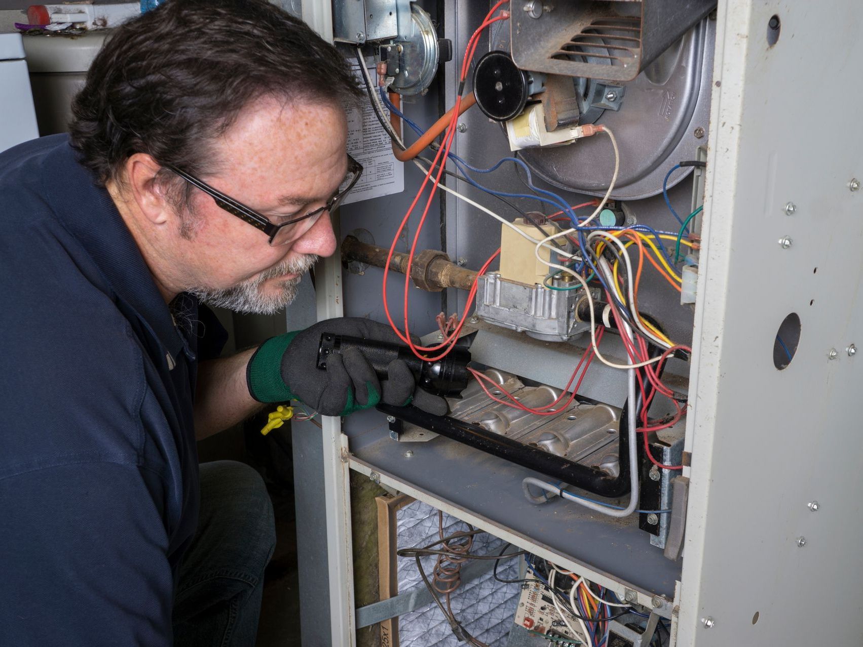 Technician inspecting exposed electrical wiring inside a control panel cabinet