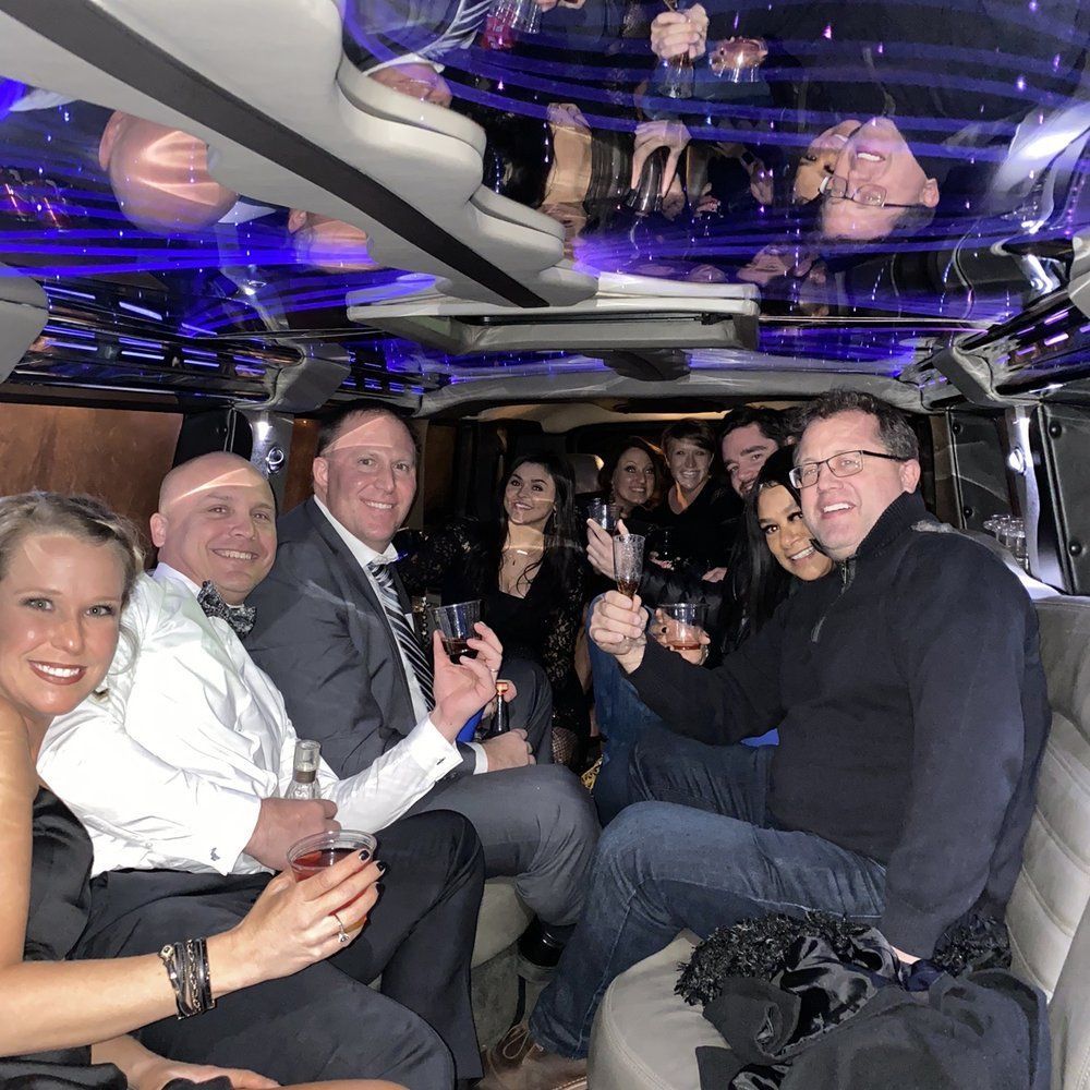 A group of people are sitting in a limousine toasting with wine glasses.