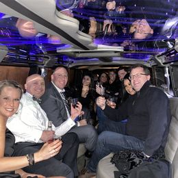 A group of people are sitting in a limousine toasting with wine glasses.