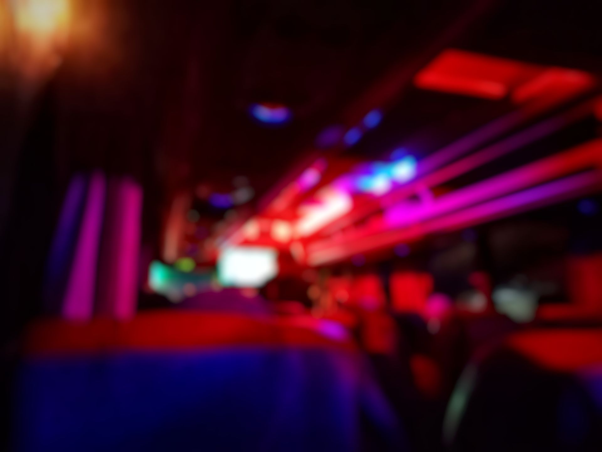 A blurry picture of a nightclub with red , purple and blue lights.
