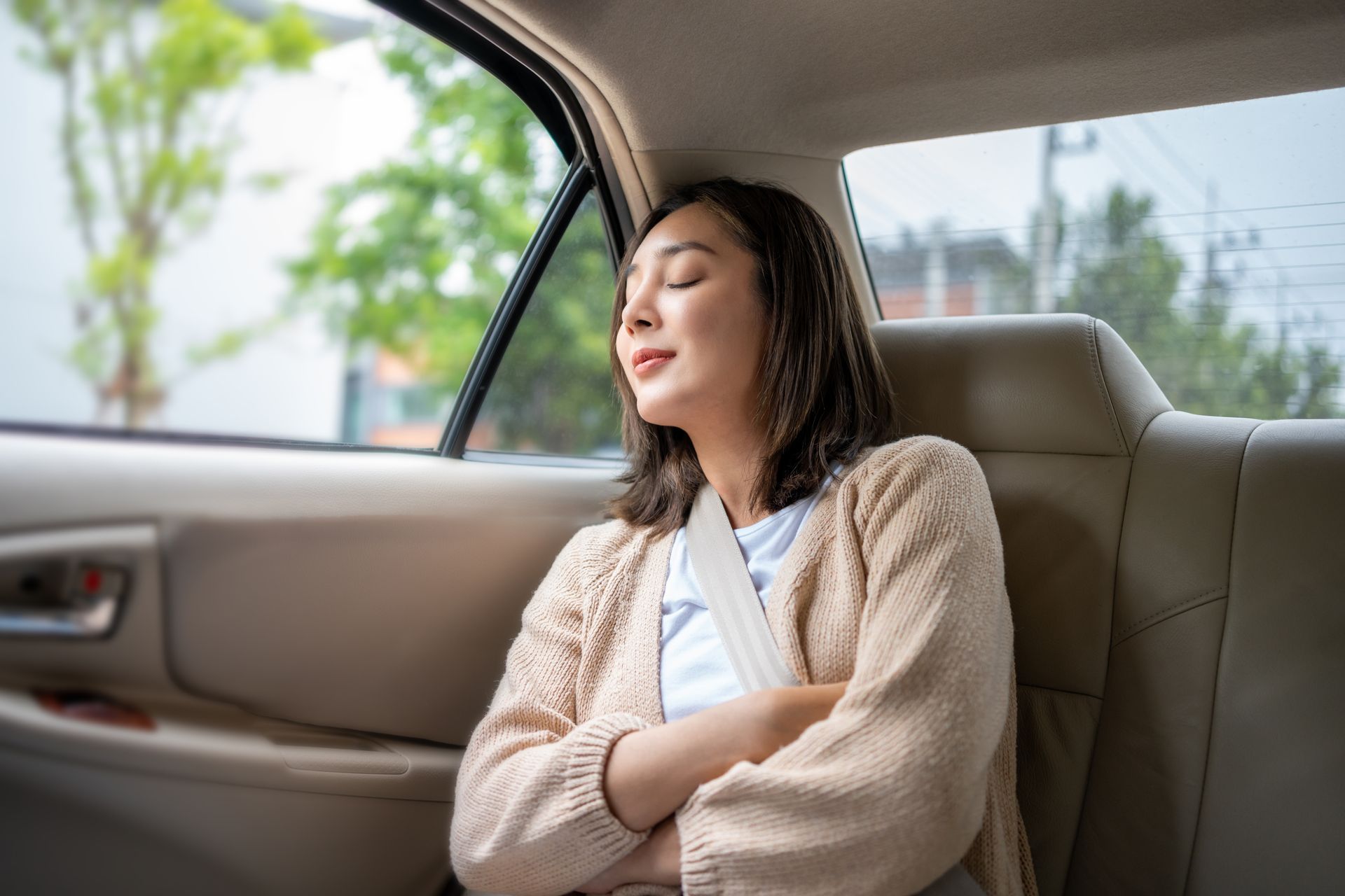 A woman is sleeping in the back seat of a car.