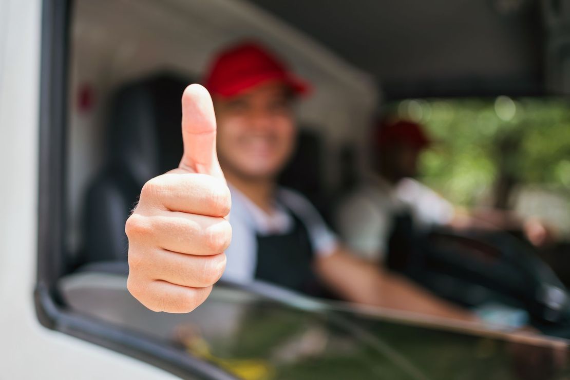 Thumbs-up gesture from a person in a red cap sitting in a truck window