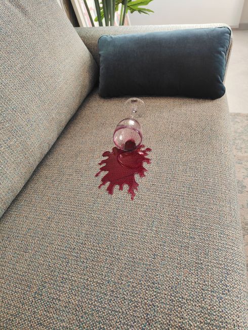 Un bicchiere di vino rovesciato su un divano.