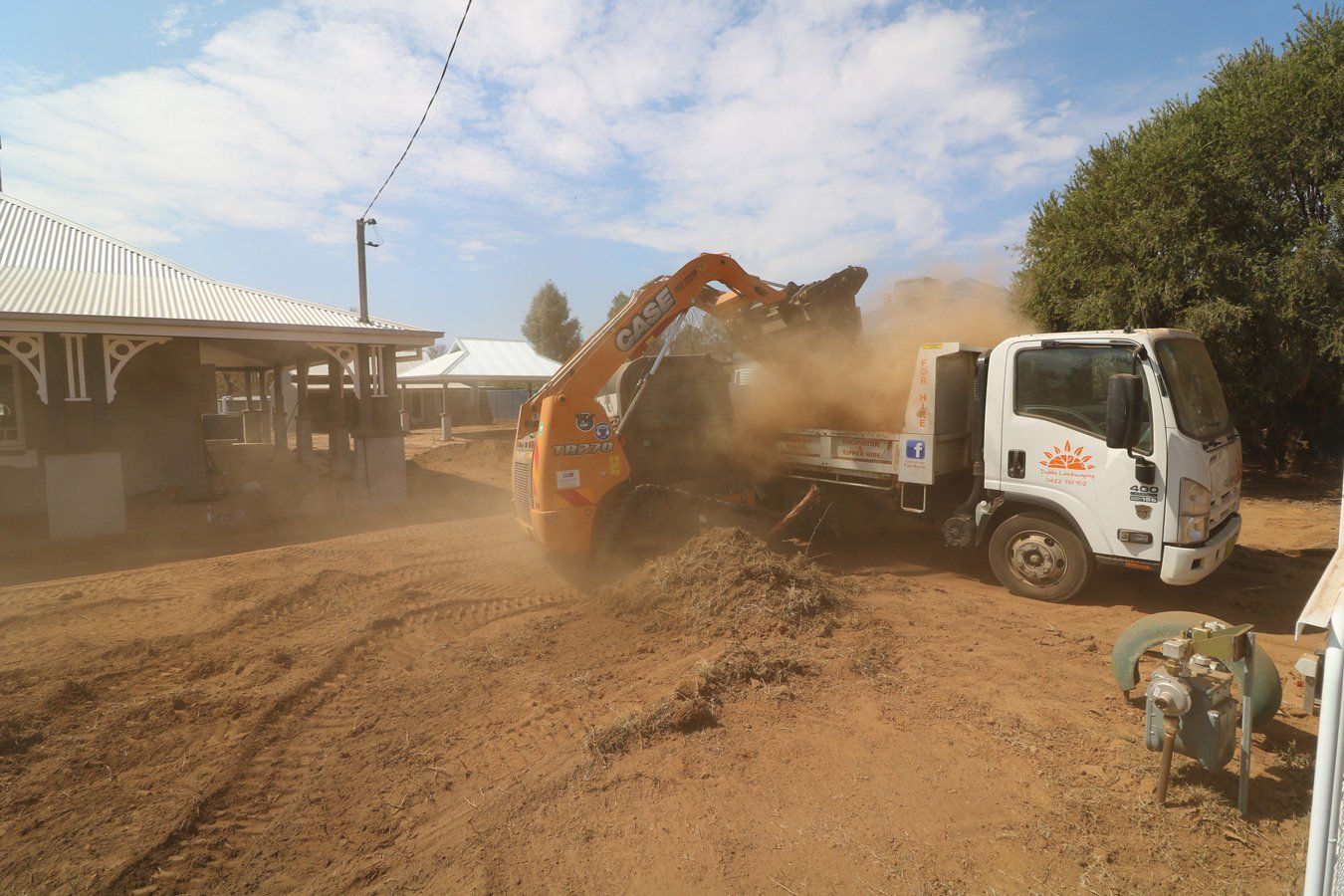 orange backhoe dumpin sad into truck