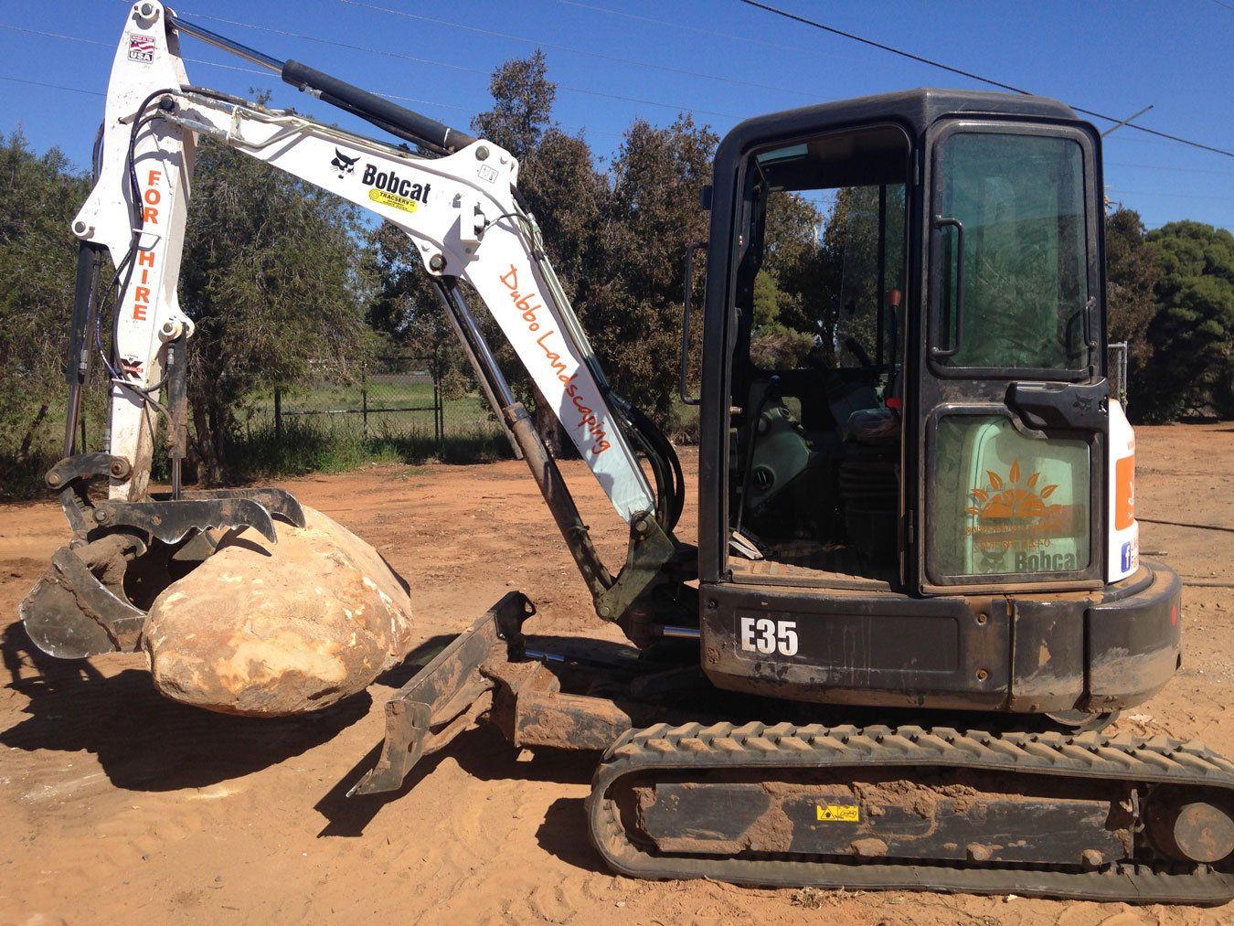 white backhoe lifting big rock