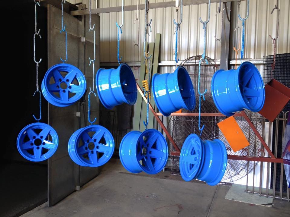 A Bunch Of Blue Wheels Are Hanging From Hooks In A Room — Hunter Powder & Paints In Muswellbrook, NSW