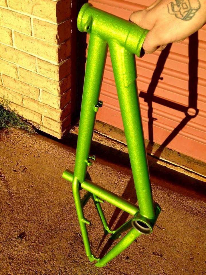 A Person With A Tattoo On Their Arm Is Holding A Green Bicycle Frame — Hunter Powder & Paints In Scone, NSW
