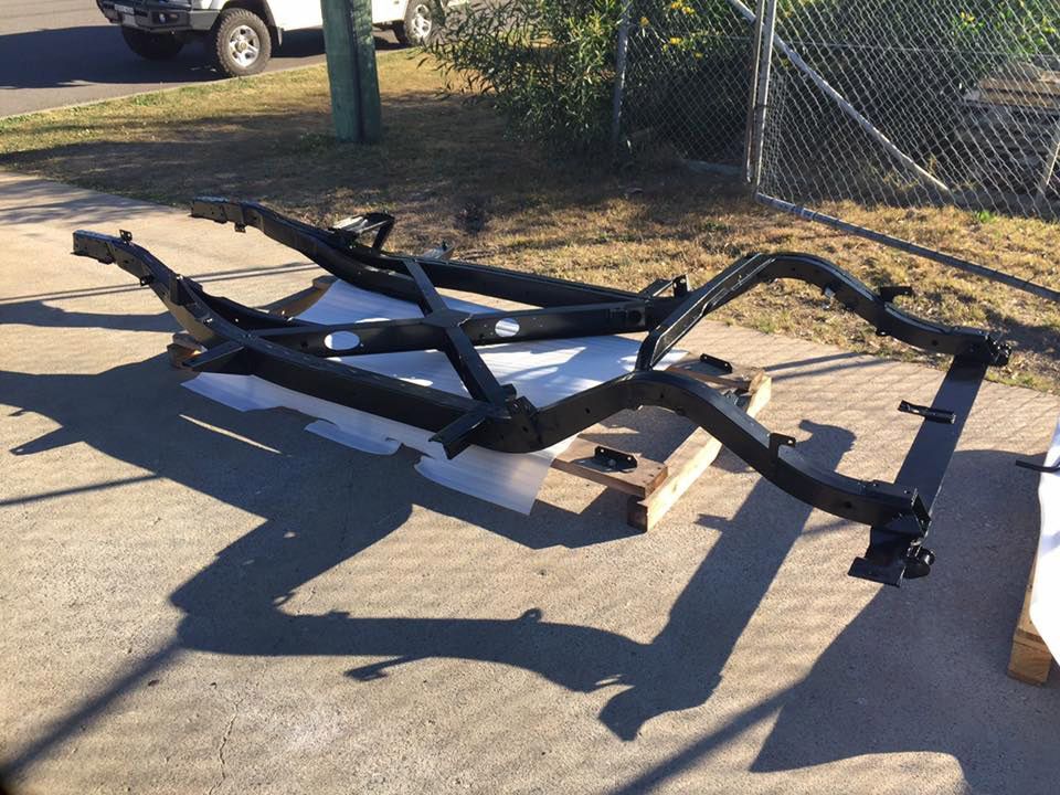 A Car Frame Is Sitting On The Ground In Front Of A Chain Link Fence — Hunter Powder & Paints In Rutherford, NSW