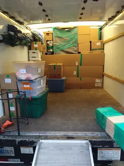 Inside a moving truck filled with packed boxes and bins ready for transport.