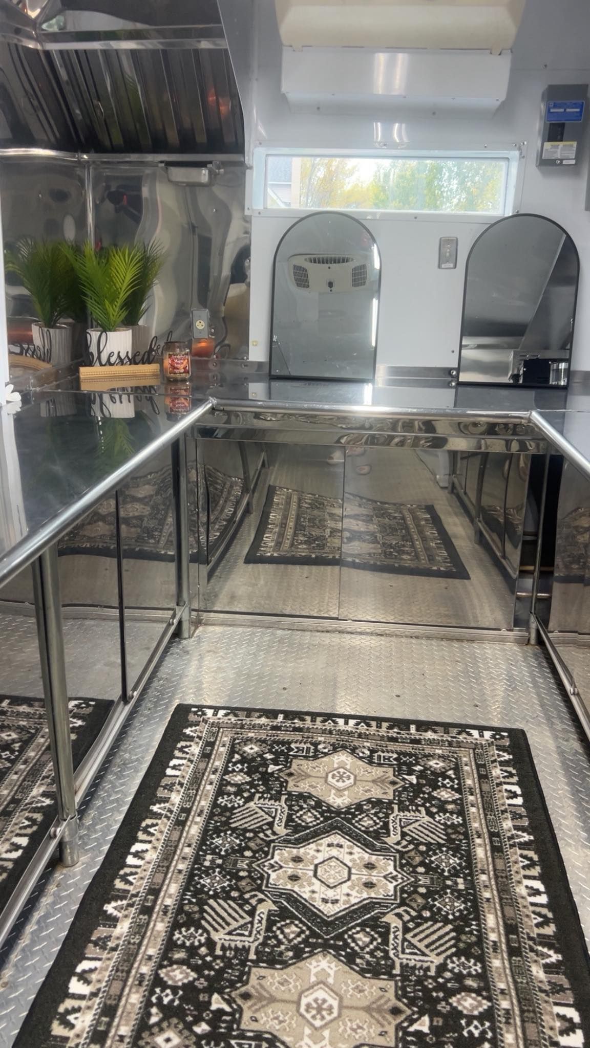 Commercial kitchen with stainless steel counters and patterned rugs.