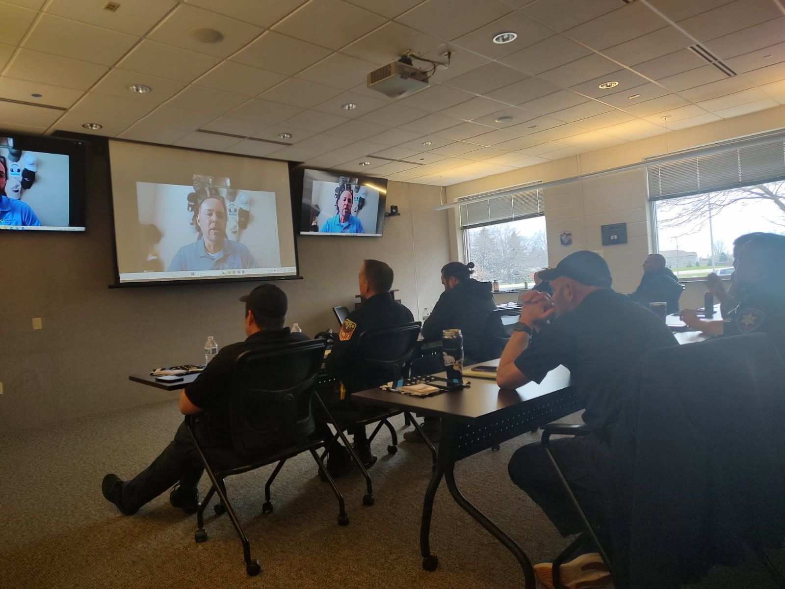 A group of people are sitting at tables in front of a projector screen
