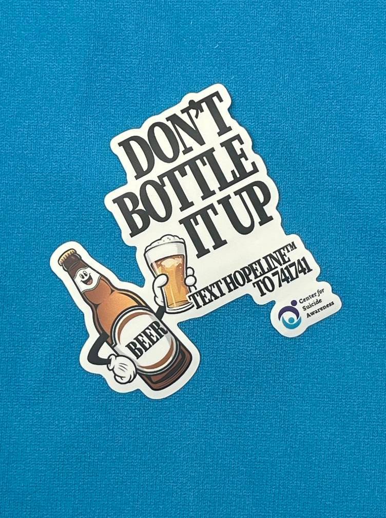 A blue shirt with a sticker on it that says `` do n't bottle it up ''.