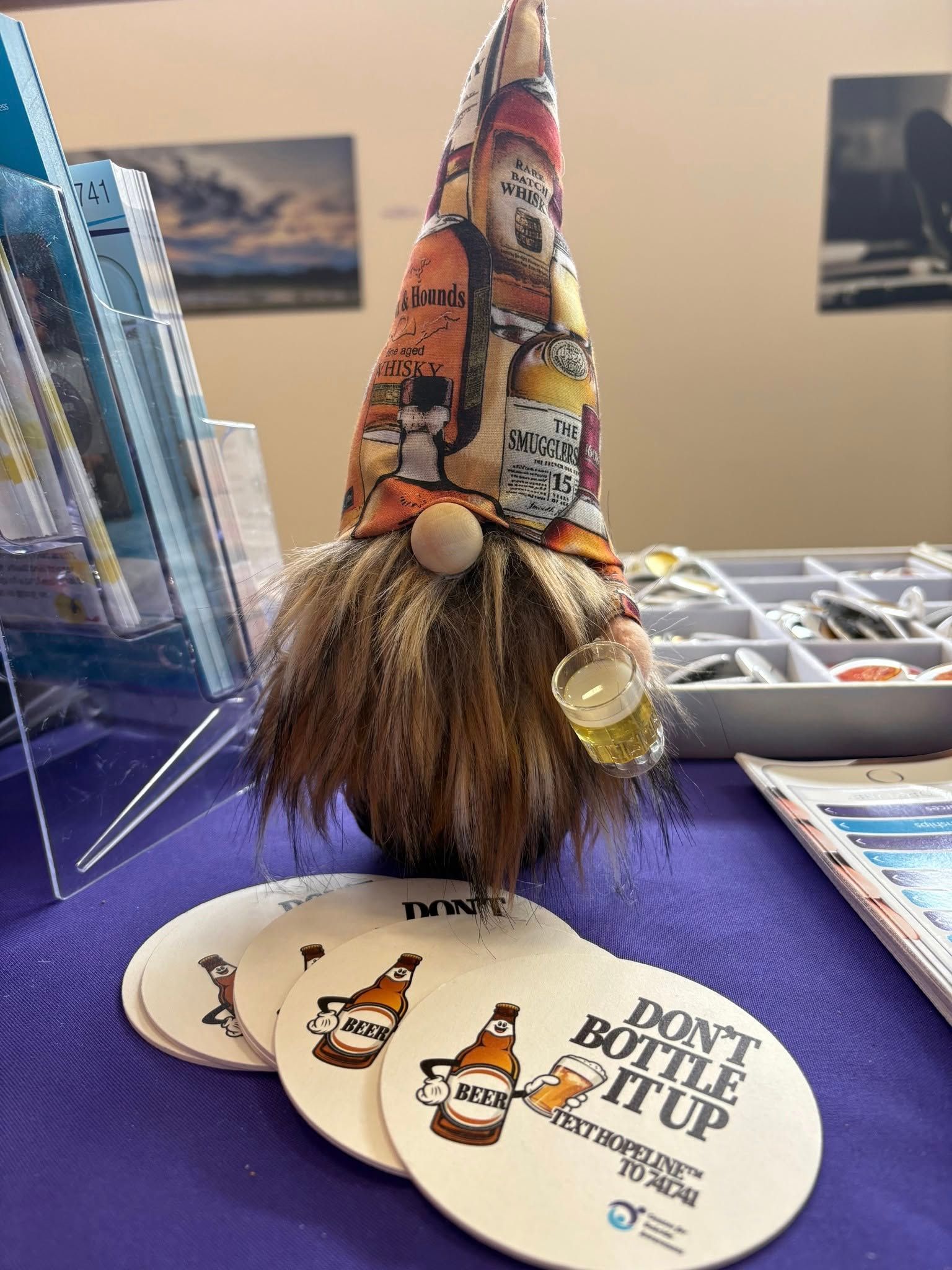 A gnome is sitting on a table next to a stack of coasters.